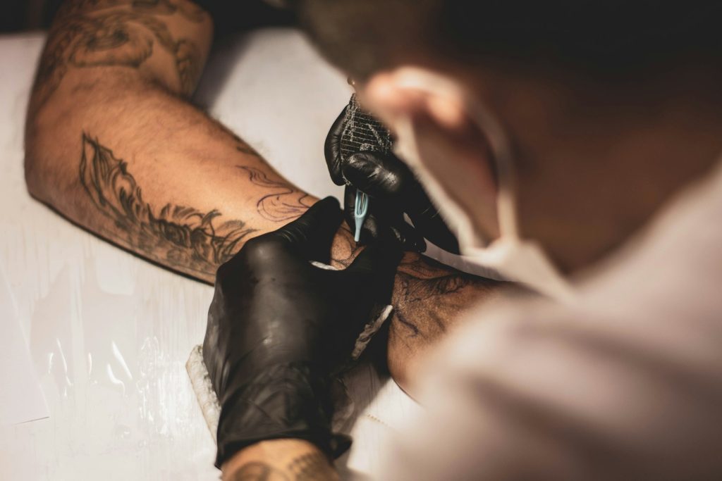 shallow focus photo of person tattooing person's right arm